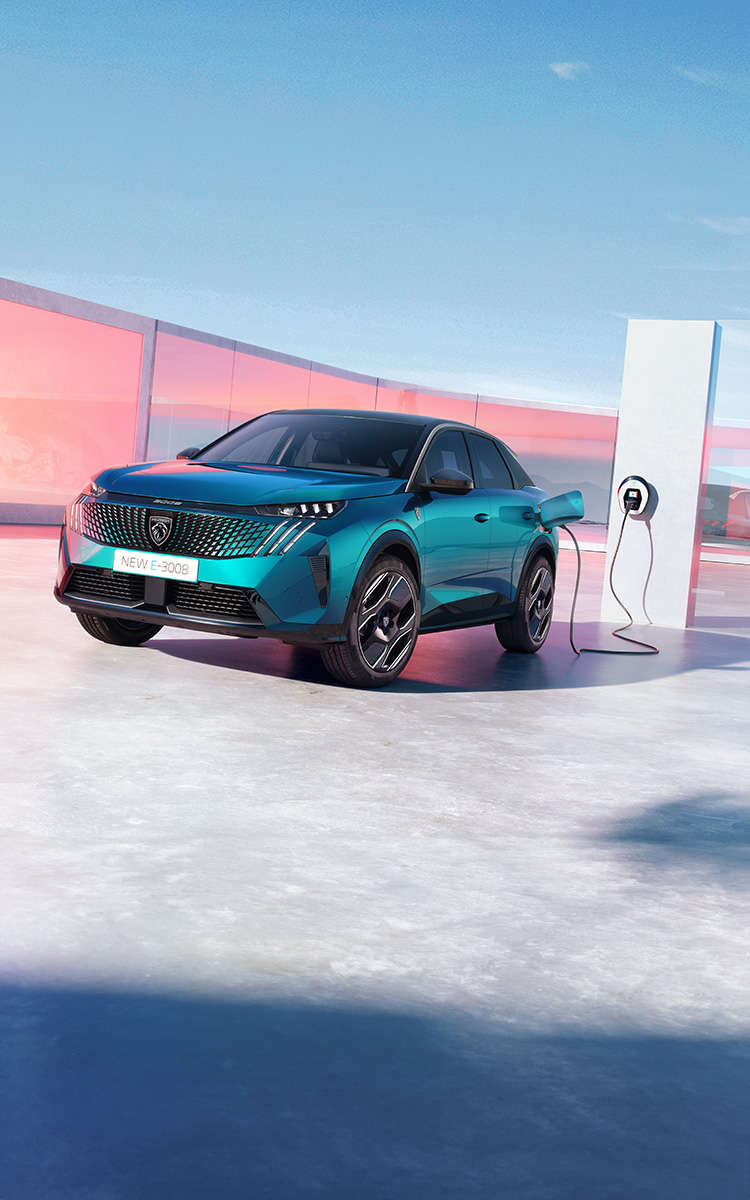 Peugeot e-3008 синього кольору заряджається від електромережі, вигляд спереду з лівого боку