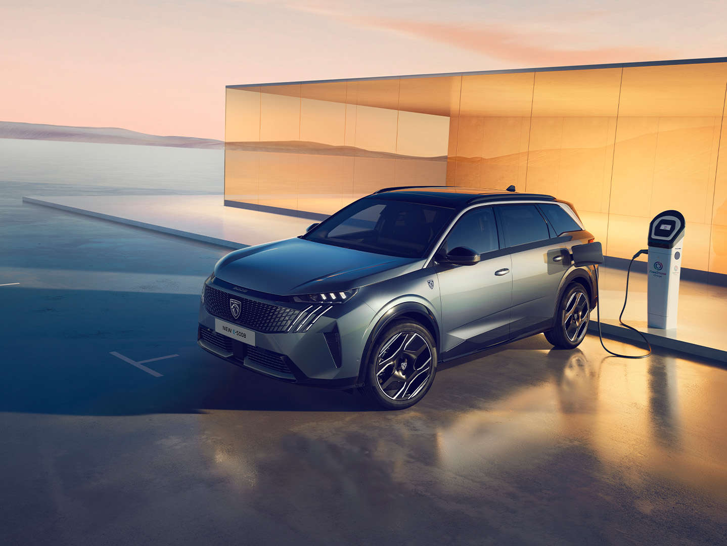 Peugeot e-5008 синього кольору заряджається від електромережі, вигляд спереду з лівого боку